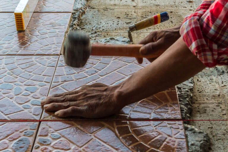 Tile being bedded into place by hand during a commercial floor installation