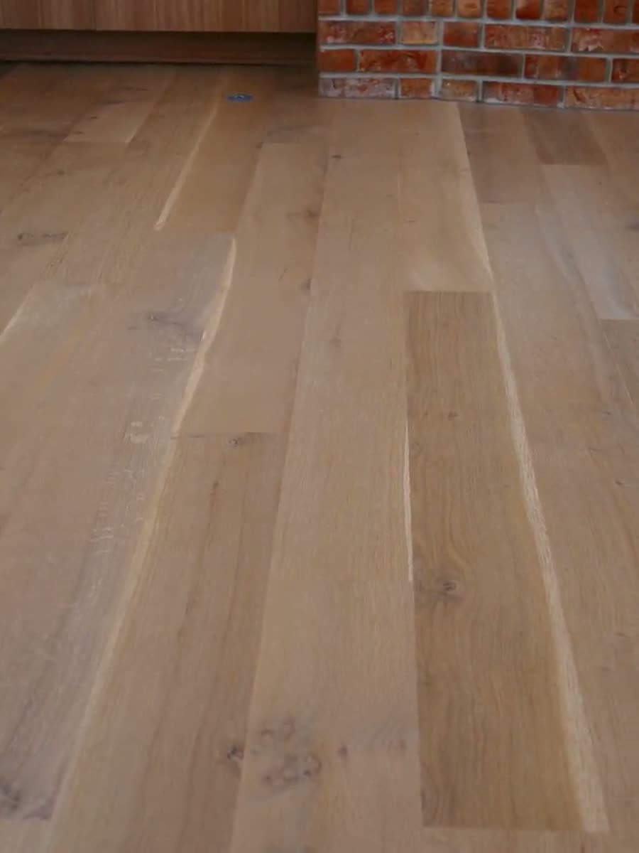 Finished wide-plank wood floor running up to an exposed red brick wall