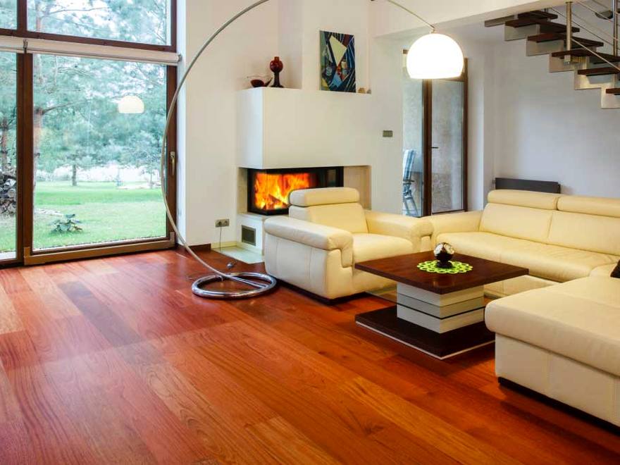 Living room floored in cherry hardwood, running past the fireplace to a wall of glass