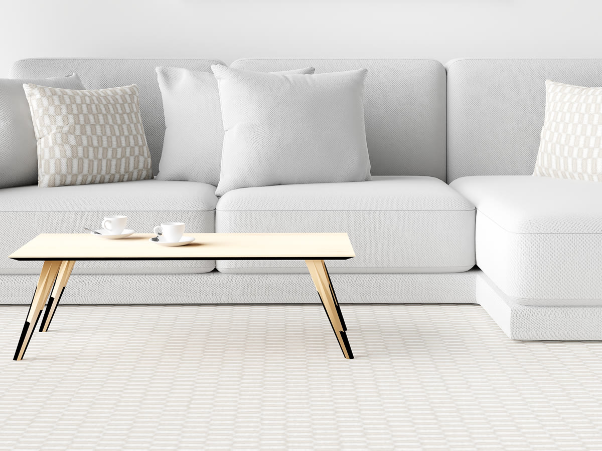 Pale wall-to-wall carpet running under a sofa