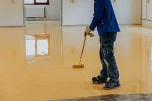 Contractor spreading an epoxy floor coating across a concrete floor