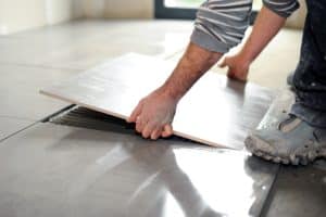 Installer hands lifting and resetting a floor tile