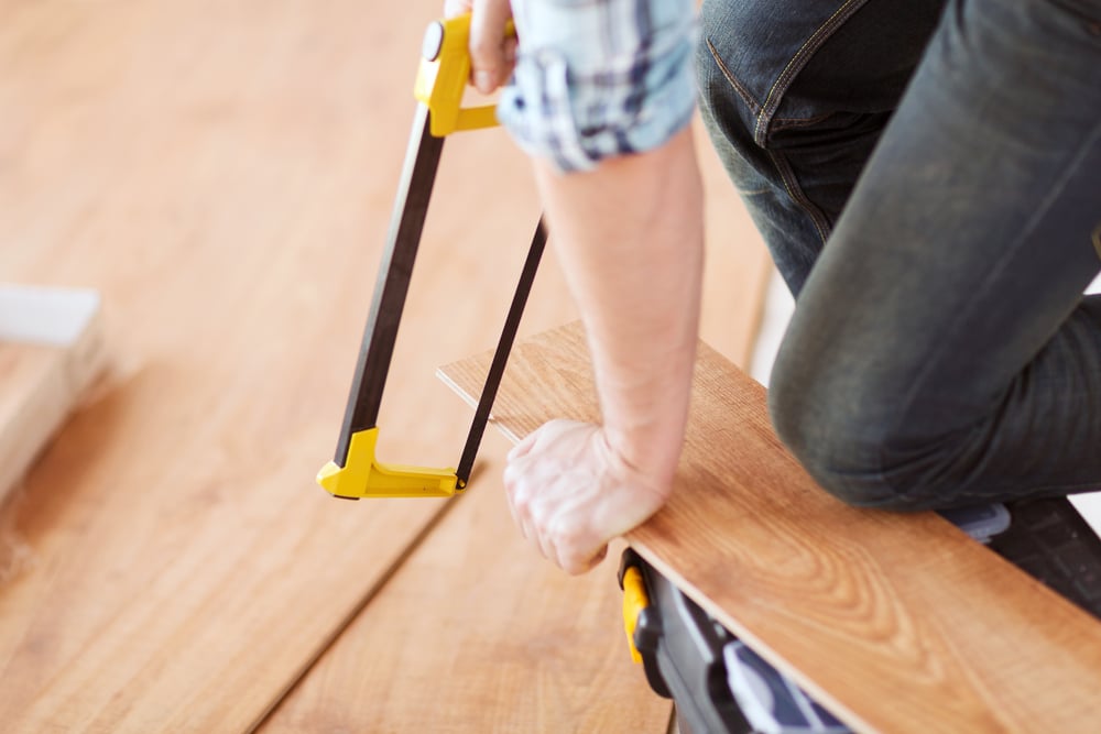 close up of male hands cutting parquet floor board